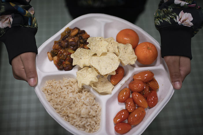 A student carries her plate which consists of three bean chili, rice, mandarins and cherry tomatoes and baked chips during her lunch break at a local public school, Friday, Feb. 10, 2023.