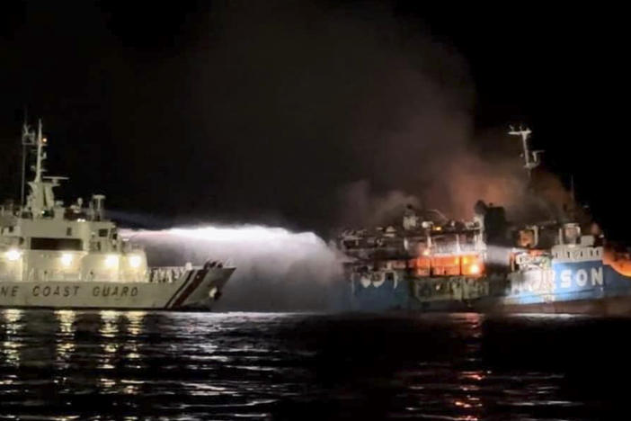 In this photo provided by the Philippine Coast Guard, a Philippine Coast Guard ship trains its hose as it tries to extinguish fire on the MV Lady Mary Joy at Basilan, southern Philippines early Thursday March 30, 2023.