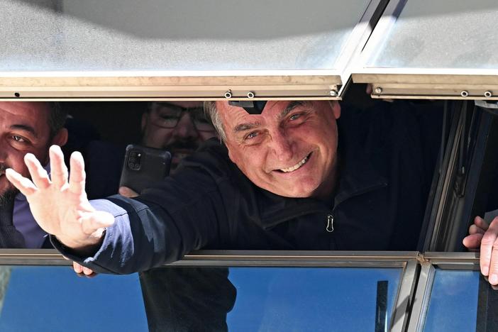 Former Brazilian President Jair Bolsonaro greets supporters from a window at the Liberal Party headquarters in Brasília on Thursday after arriving back in Brazil on a commercial flight from Orlando, Fla.