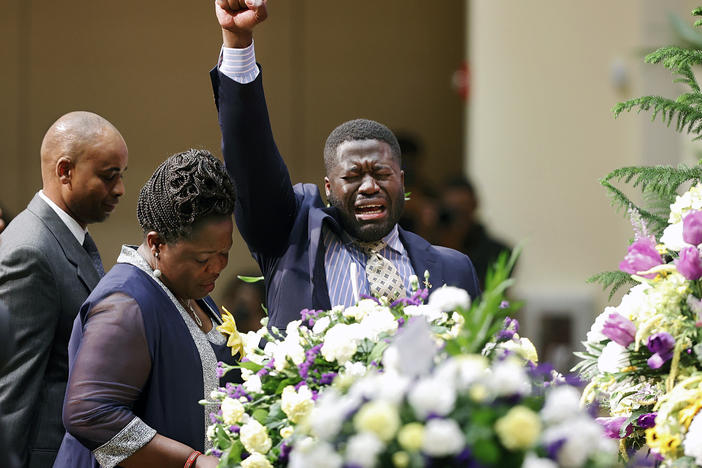 Caroline Ouko, center, and Leon Ochieng, right, the mother and older brother of Irvo Otieno, stand with his casket during his funeral on Wednesday.