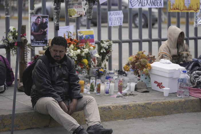 A Venezuelan migrant sits on the sidewalk where an altar was created with candles and photos outside the Mexican immigration processing center that was the site of a deadly fire, as migrants wake up after spending the night on the sidewalk in Ciudad Juárez, Mexico, on Thursday.