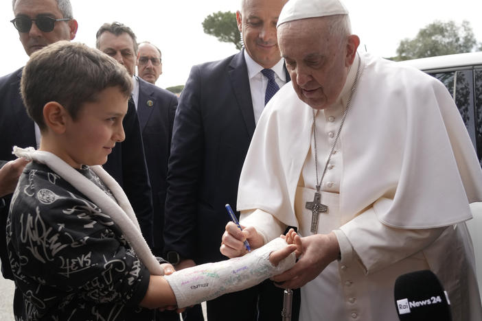 Pope Francis autographs the plaster cast of a child as he leaves the Agostino Gemelli University Hospital in Rome on Saturday.