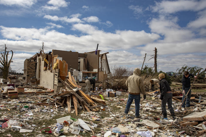 Family and neighbors look through debris on Ed Whestine's farm southwest of Wellman, Iowa on Saturday. Storms that dropped possibly dozens of tornadoes killed multiple people in small towns and big cities across the South and Midwest.