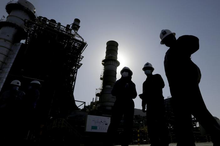 Saudi Aramco engineers walk in front of a gas turbine generator at Khurais oil field during a tour for journalists, about 93 miles east-northeast of Riyadh, Saudi Arabia, on June 28, 2021.