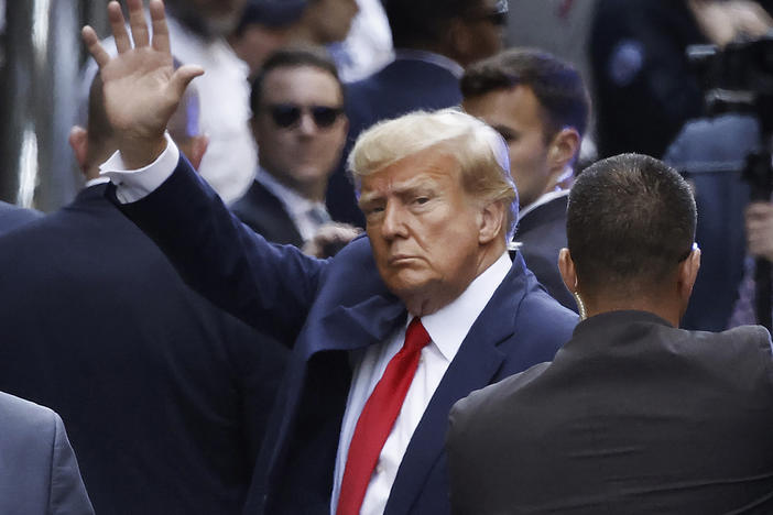 Former President Donald Trump waves as he arrives at criminal court in Manhattan for his arraignment hearing on Tuesday.