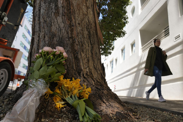 A woman on Wednesday walks past flowers left outside an apartment building in in San Francisco where technology executive Bob Lee was fatally stabbed.