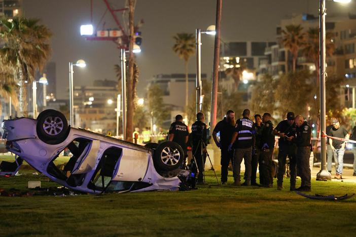 Israeli police gather next to an overturned car at the site of an attack Friday in Tel Aviv in which an Italian tourist was killed and several other people were injured.