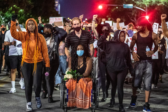 Whitney Mitchell (center), Garrett Foster's fiancée, leads a march for Foster in July of 2020, after Foster was shot and killed at a Black Lives Matter protest. Sgt. Daniel Perry has been found guilty of murdering Foster — but Gov. Greg Abbott wants to pardon Perry.