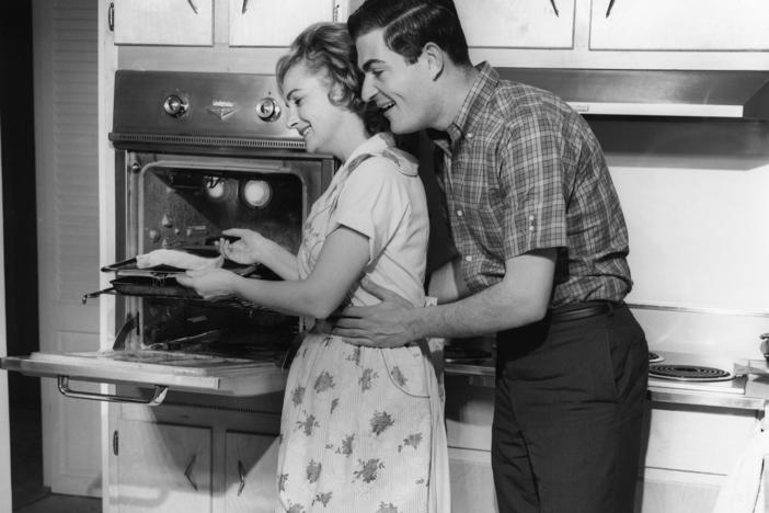 UNITED STATES - CIRCA 1950s: Couple in kitchen. Women in opposite-sex marriages may be contributing more to their families' income, but they're also still shouldering more of the workload at home, according to a new report.