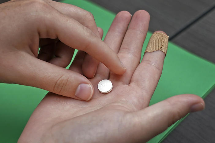 A patient prepares to take the first of two pills for a medication abortion during a visit to a clinic in Kansas City, Kan., on Wednesday, Oct. 12, 2022.