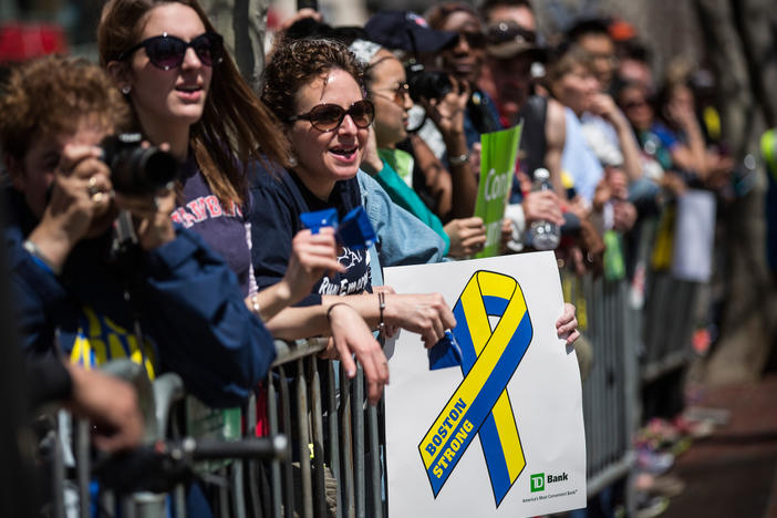 Fans with a "Boston Strong" poster cheer on runners as they finish the Boston Marathon in April 2014.