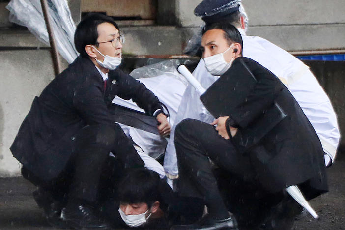 A person (bottom) is detained after throwing an apparent "smoke bomb" in Wakayama on Saturday, where Japan's prime minister was due to give a speech.