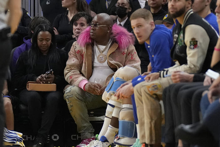 E-40, middle, watches during an NBA basketball game between the Golden State Warriors and the Portland Trail Blazers in San Francisco, Dec. 30, 2022. The Sacramento Kings are investigating allegations from the rapper E-40 that "racial bias" led to him being kicked out of his seat during a playoff game against the Golden State Warriors.