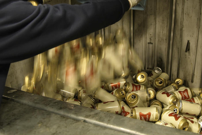 A worker dumps empty cans of Miller High Life beer into a machine to be crushed at the Westlandia plant in Ypres, Belgium, on Monday.