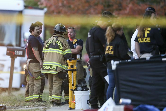 Police and firefighters investigate the scene of a house fire where eight people were found dead in Broken Arrow, Okla., on Oct. 27, 2022.