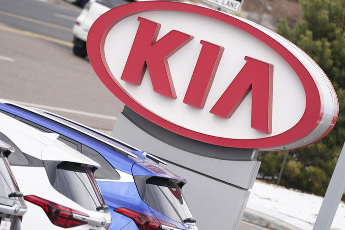 A Kia sign hangs over a row of unsold 2021 Seltos models in December 2020 at a dealership in Centennial, Colo.