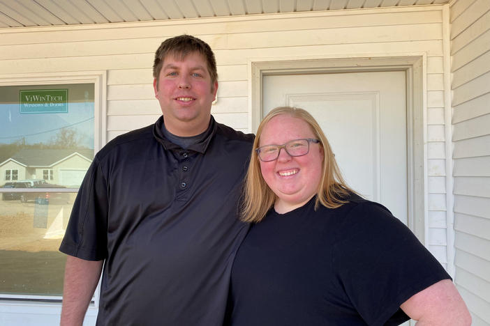 Cook employees Ryan and Shelby Bixler stand in front of the house they're buying from the company. They say they never could have afforded a new place like this at the full market price.