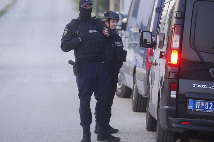 Police officers stand guard on a road in the village of Dubona, some 50 kilometers (30 miles) south of Belgrade, Serbia, Friday, May 5, 2023, as they block the road near the scene of a Thursday night attack.