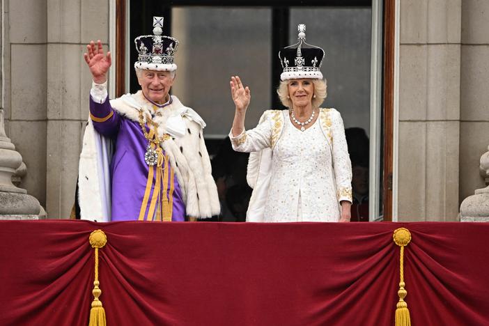 Britain's King Charles III wearing the Imperial state Crown, and Britain's Queen Camilla wearing a modified version of Queen Mary's Crown wave from the Buckingham Palace balcony after viewing the Royal Air Force fly-past in central London.
