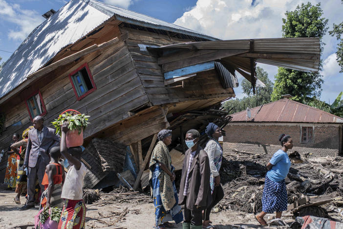 People walk next to a house destroyed by the floods in the village of Nyamukubi, South Kivu province, in Congo, Saturday, May 6, 2023. The death toll from flash floods and landslides in eastern Congo has risen according to the governor and authorities in the country's South Kivu province.