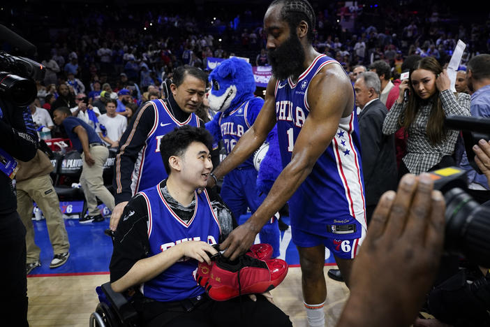 Philadelphia 76ers' James Harden gives his sneakers to John Hao after Game 4 in an NBA basketball Eastern Conference semifinals playoff series, Sunday, May 7, 2023, in Philadelphia. Harden invited Hao, a student severely wounded in a Feb. 13 mass shooting at Michigan State University, to view the game.