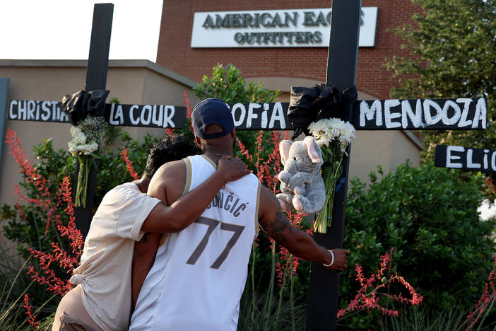 Robert Jackson and his mother, Cheryl Jackson, hug Monday as they visit a memorial near the scene of a mass shooting at the Allen Premium Outlets mall in Allen, Texas.