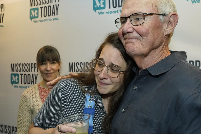 Mississippi Today reporter Anna Wolfe, center, is congratulated Monday by staff sports columnist Rick Cleveland, right, after winning the 2023 Pulitzer Prize for Local Reporting, as her mother, Bethel Wolfe, left, observes, at a celebration in Jackson, Miss. Wolfe was honored for her reporting on a $77 million welfare scandal, the largest embezzlement of federal funds in Mississippi's history.