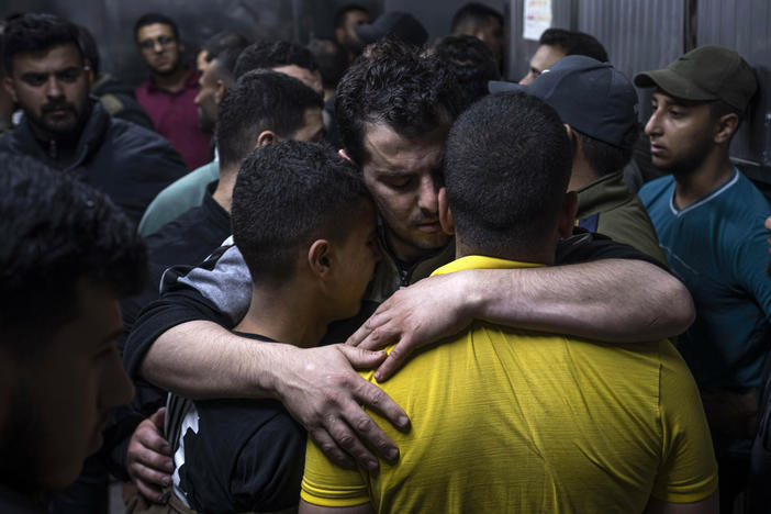 Mourners comfort each other in the morgue of Al-Shifa Hospital after Israeli airstrikes killed a dozen Palestinians in Gaza City, Tuesday, May 9, 2023.