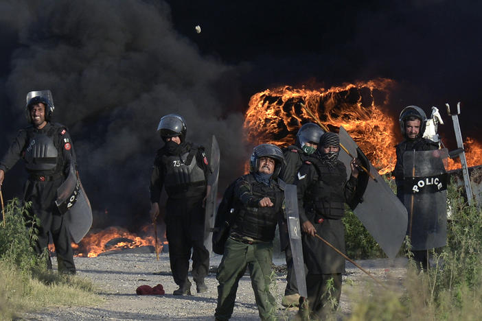 Police officers throw stones toward supporters of Pakistan's former Prime Minister Imran Khan during clashes in Islamabad on Wednesday. Khan's arrest on Tuesday sparked violence in major cities. On Thursday, the Supreme Court ordered Khan's release.