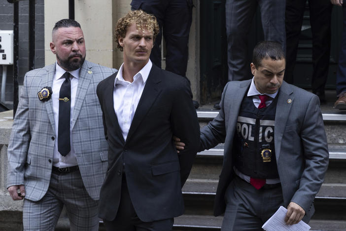 Daniel Penny, center, is escorted by police after turning himself in for manslaughter charges in the death of Jordan Neely.