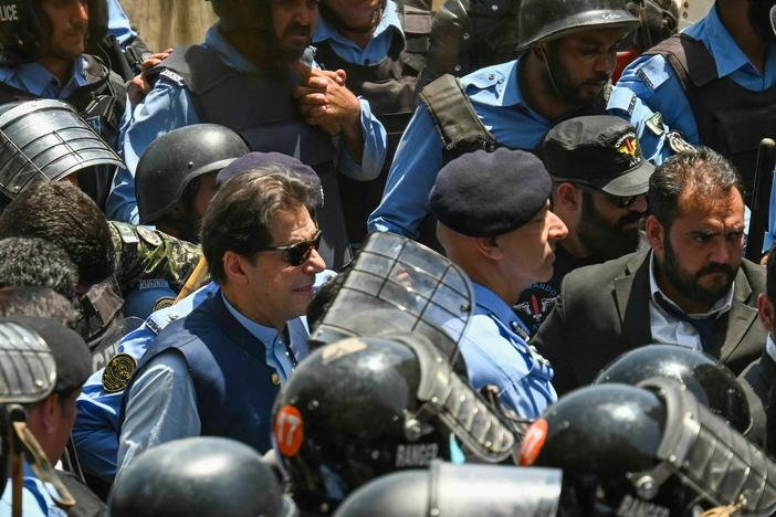 Policemen escort Pakistan's former Prime Minister Imran Khan as he arrives at the high court in Islamabad on Friday.