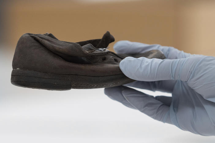 A worker holds a shoe that belonged to a child victim of the former Nazi German death camp Auschwitz-Birkenau at the conservation laboratory on the grounds of the camp in Oswiecim, Poland, Wednesday, May 10, 2023.