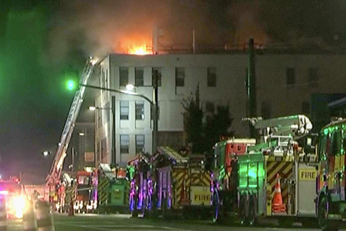In this image made from video, firetrucks stage outside a hostel in central Wellington, New Zealand, early Tuesday, May 16, 2023. Several people were killed after a fire broke out overnight at the four-story building.