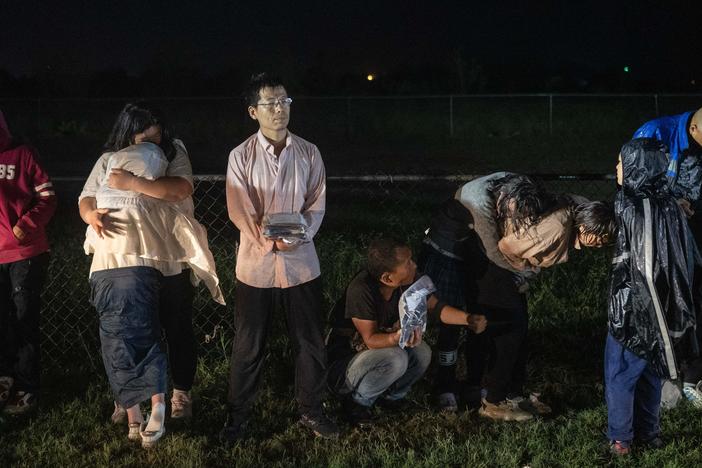 Migrants try to stay warm as they wait in the rain after turning themselves over to U.S. Border Patrol agents after crossing over from Mexico in Fronton, Texas on May 12.