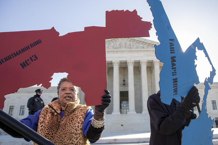 Demonstrators opposed to partisan gerrymandering hold up representations of congressional districts from North Carolina (left) and Maryland (right) outside the U.S. Supreme Court in Washington, D.C., in 2019.