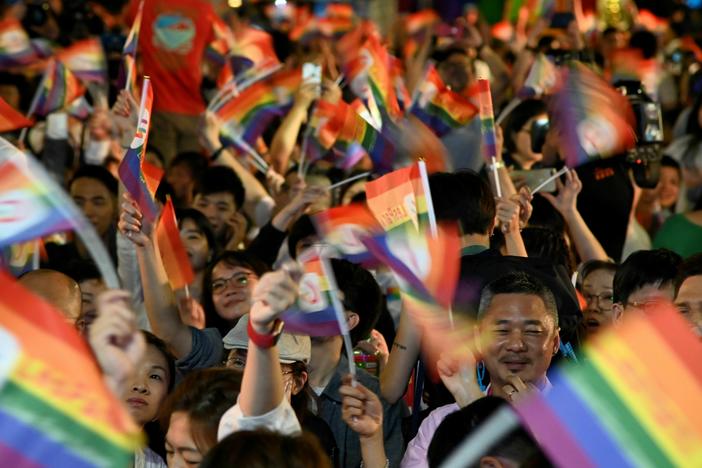 People wave rainbow flags during a mass wedding banquet for gay couples in front of the Presidential Palace in Taipei in 2019. Taiwan legalized gay marriage in 2019. But until now, those married couples could only adopt children related to one of the partners.