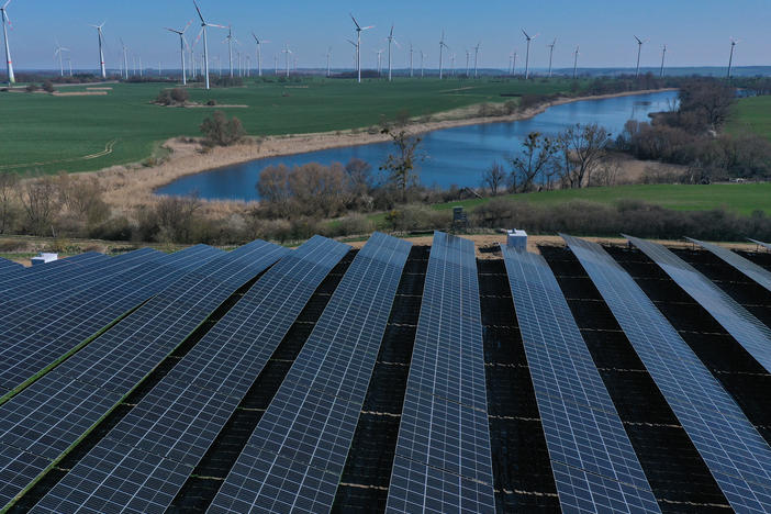 Newly installed solar panels face the sky at the construction site of a new solar energy park as wind turbines spin behind last month near Prenzlau, Germany.