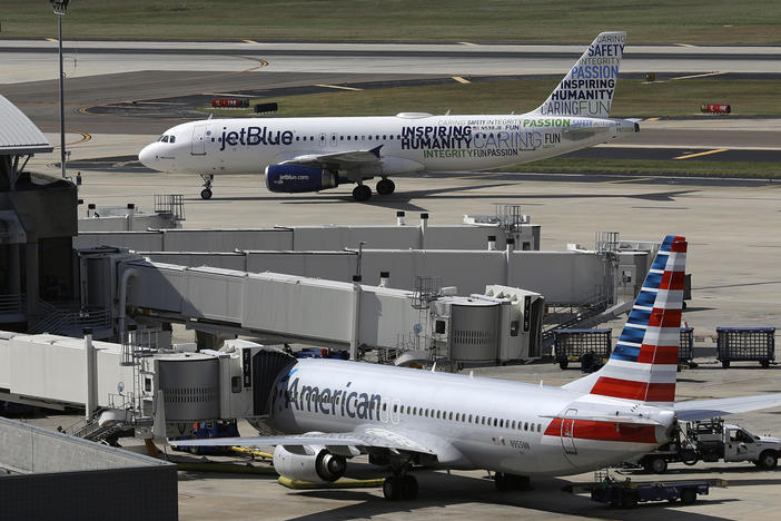 A JetBlue Airbus A320 taxis to a gate on Oct. 26, 2016, after landing, as an American Airlines jet is seen parked at its gate at Tampa International Airport in Tampa, Fla.