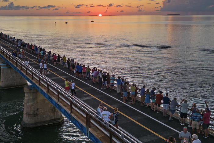 In this aerial photo provided by the Florida Keys News Bureau, attendees watch and toast the sunset at a Florida Keys bicentennial celebration, Friday, May 19, 2023, on the restored Old Seven Mile Bridge in Marathon, Fla.