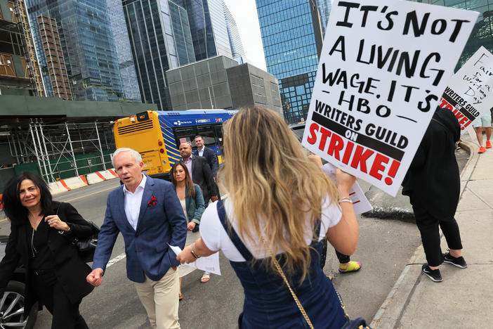Writers Guild of America East members hand out flyers as they walk a picket line in New York on May 16.