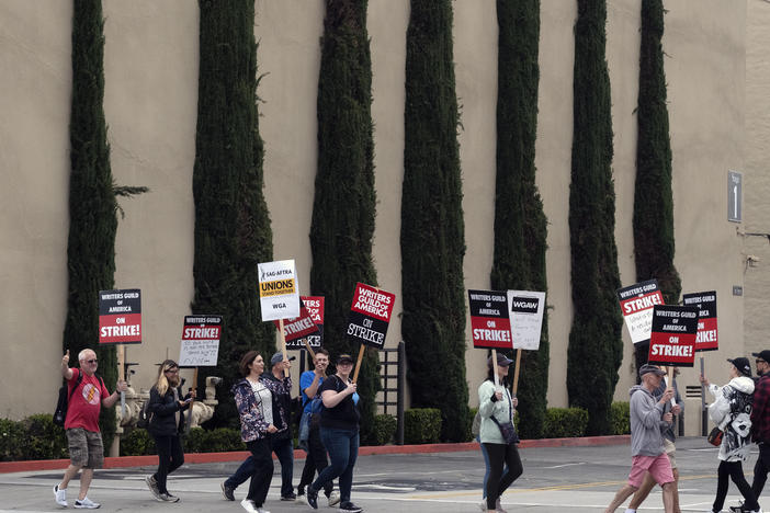 Picketers pass near stage 5 at a studio entrance during a Writers Guild rally outside Warner Bros. Studios, on Wednesday, in Burbank, Calif.