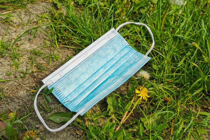 A face mask languishes in the grass in Krakow, Poland. With the state of emergency over, some people are relishing freedom from masks while others believe masking up is still a wise preventive measure.