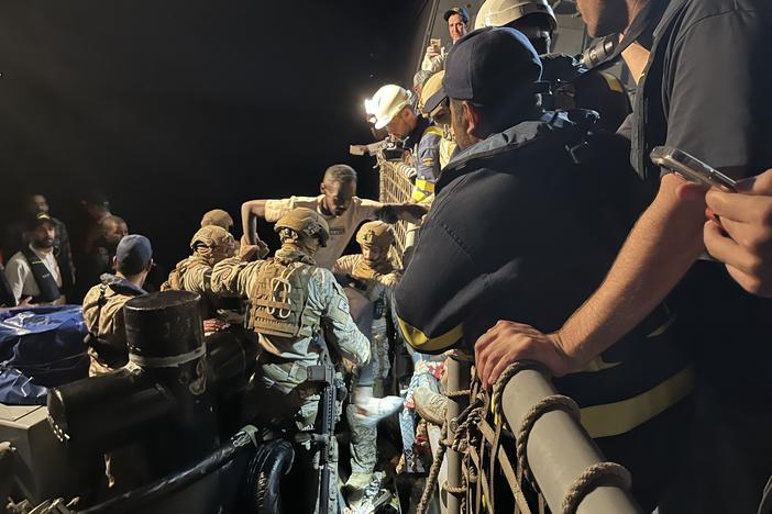 A man is assisted by Saudi commandos as he gets off a tugboat near Port Sudan and onto a Saudi warship that will travel across the Red Sea to Jeddah, Saudi Arabia. May ‎2, ‎2023.