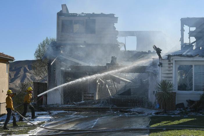 Firefighters hose down a burning house during the Tick Fire in Agua Dulce near Santa Clarita, Calif., in October 2019.
