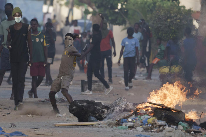A demonstrator throws a rock at police during a protest at a neighborhood in Dakar, Senegal, on Saturday. The clashes first broke out after opposition leader Ousmane Sonko was convicted of corrupting youth and sentenced to two years in prison.