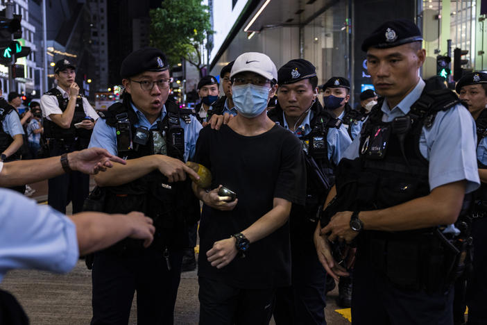 A member of the public is escorted by police after shining the light from a smartphone, near Victoria Park, the city's venue for the annual 1989 Tiananmen massacre vigil, on the 34th anniversary of China's Tiananmen Square crackdown in Hong Kong on Sunday.