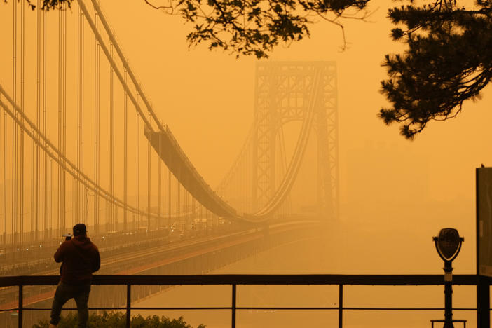 A man talks on his phone as he looks through the haze at the George Washington Bridge from Fort Lee, N.J., on Wednesday.