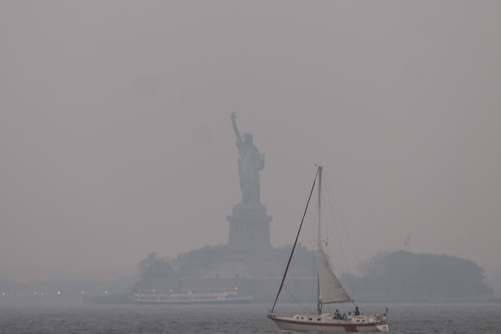 The Statue of Liberty stands shrouded in a reddish haze as a result of Canadian wildfires on Tuesday.