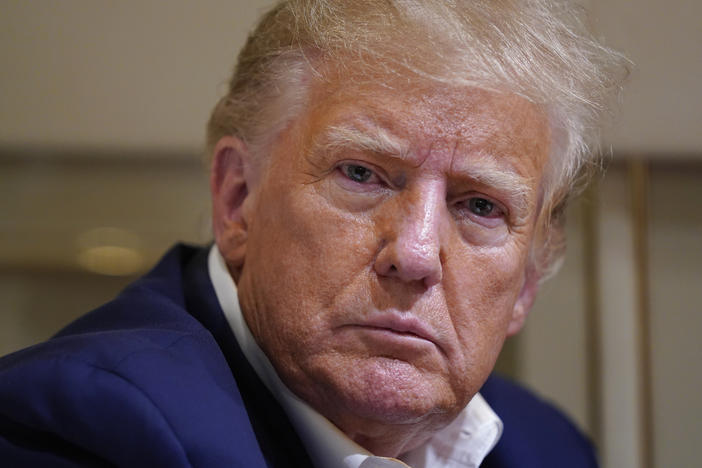 Former President Donald Trump listens as he speaks with reporters while in flight on his plane after a campaign rally in Waco, Texas, on March 25.