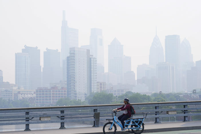 A person cycles past the skyline in Philadelphia shrouded in haze on Thursday.